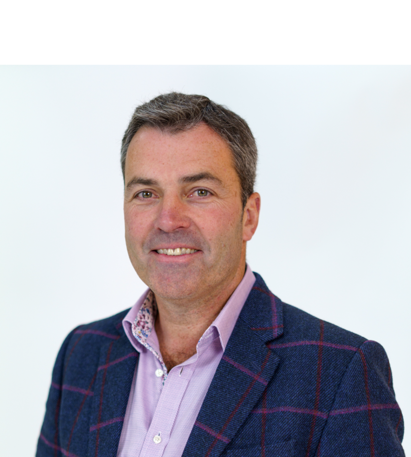 Gary Gilburd, Chief Executive Officer, Sigma Connected, South Africa, Offshore BPO Confidence Index 2023: Smiling man in a navy checked blazer and pink shirt against a white background