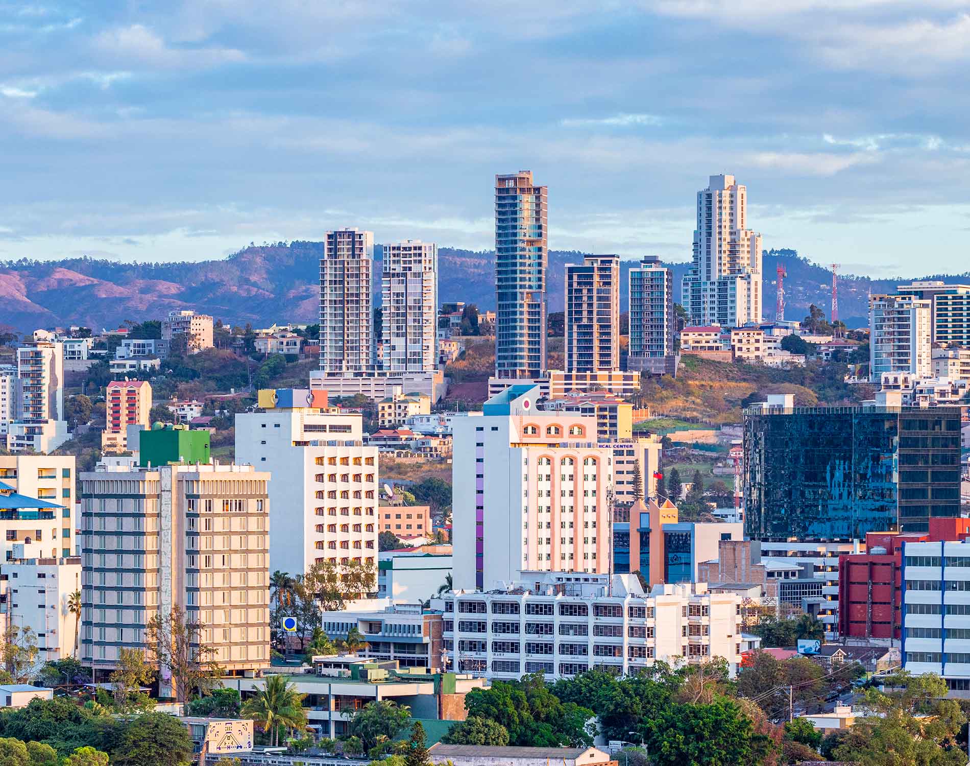 City skyline with high-rise towers and green hills under a blue sky. Honduras, Offshore BPO Confidence Index 2023