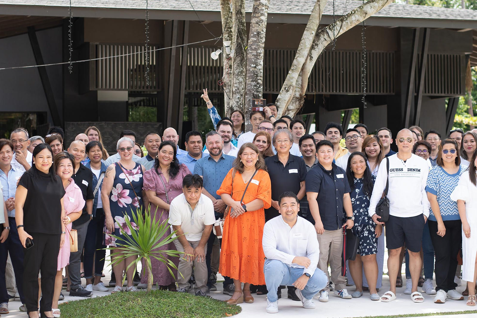 Inspiro team in Philippines, Offshore BPO Confidence Index 2023: Large group of employees in casual clothes posing together outdoors under a covered terrace