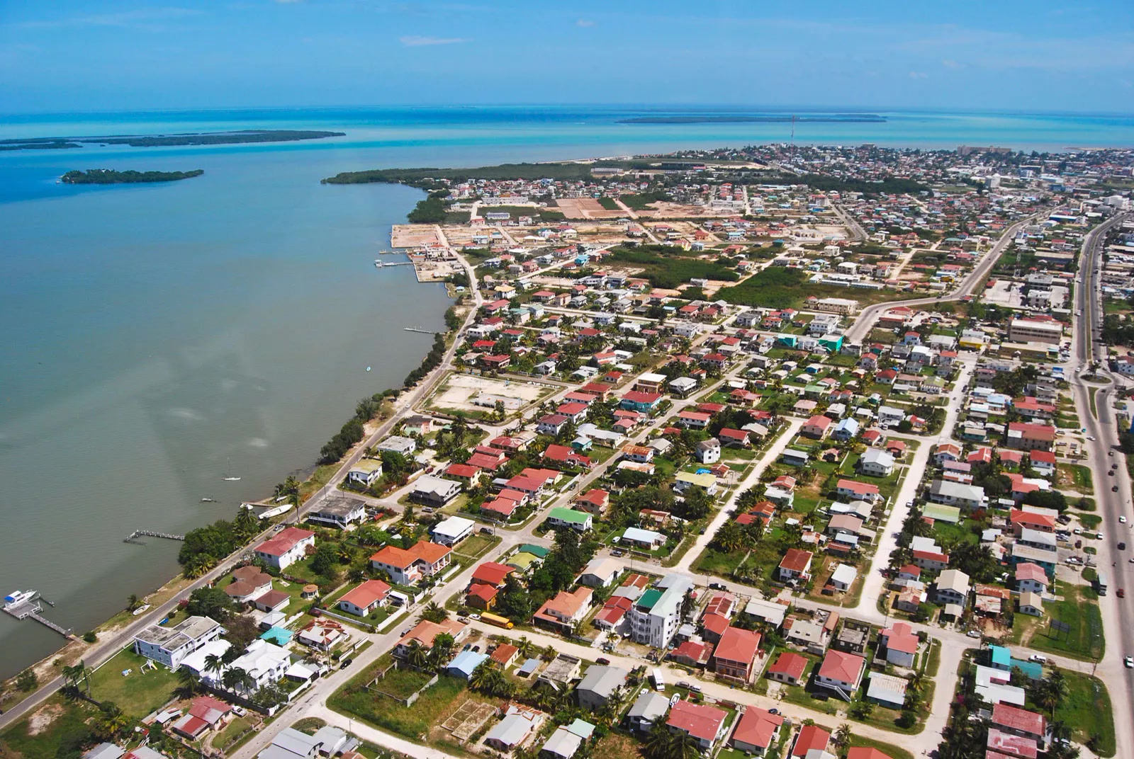 Aerial view of Belize City, Belize, with coastal houses, red rooftops, and a turquoise bay on the left. Belize, Offshore BPO Confidence Index 2024