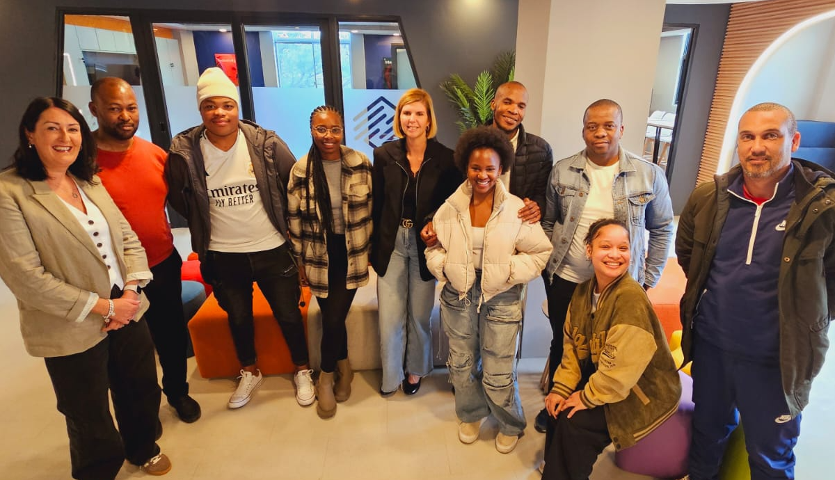 HGS South Africa team, Offshore BPO Confidence Index 2024: About ten people smiling in a bright office lounge with orange cushions and a potted plant