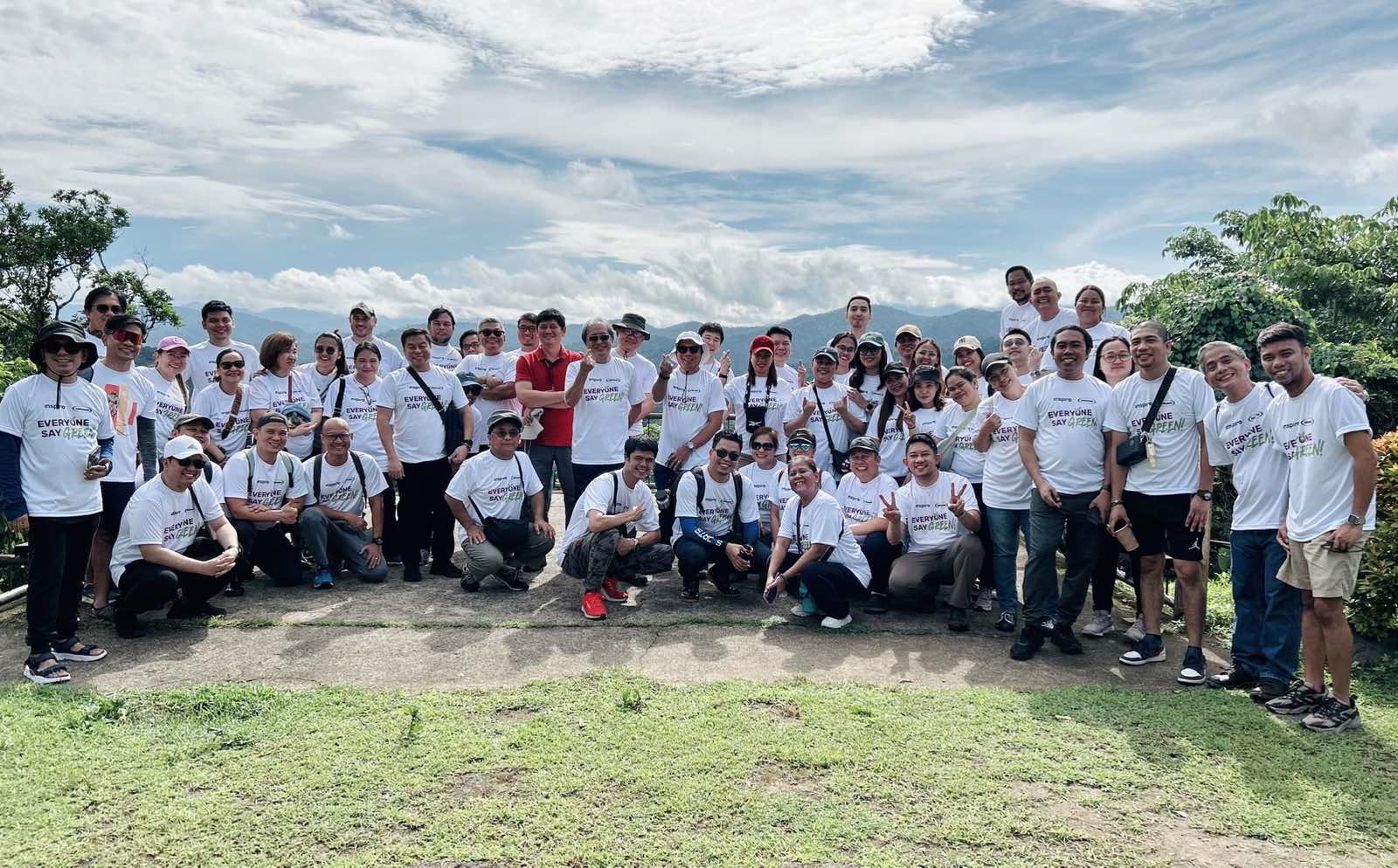 Inspiro Philippines team, Offshore BPO Confidence Index 2024: About fifty people in matching white T-shirts reading Everyone Say Green, posing outdoors on a hillside