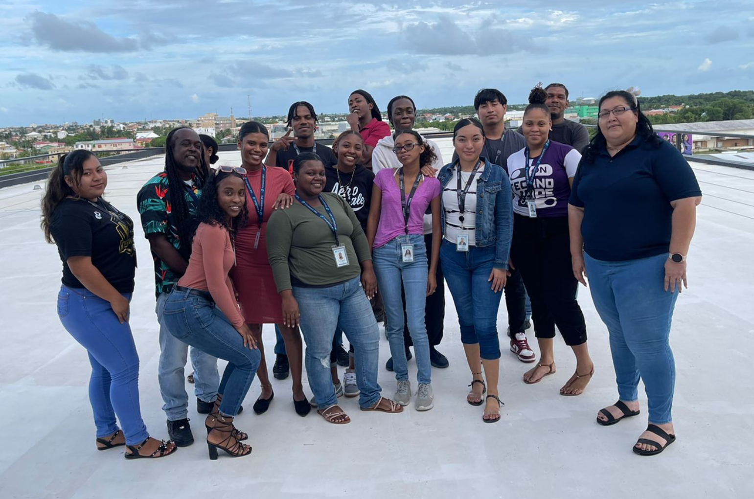 OneSource team in Belize, Offshore BPO Confidence Index 2024: About fifteen young employees and one older woman posing on a rooftop with a city skyline behind