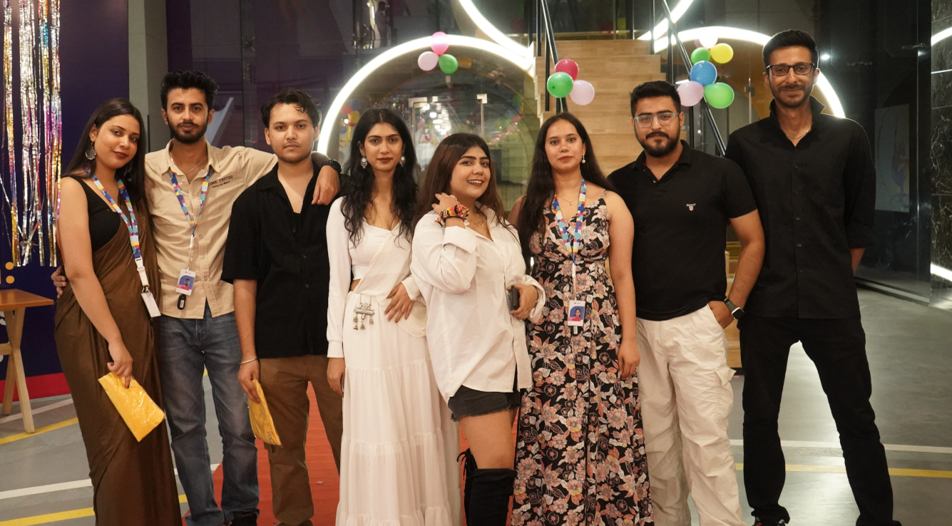 TaskUs India team, Offshore BPO Confidence Index 2024: Eight young people posing together in a glass-walled lobby decorated with balloons and glowing arches