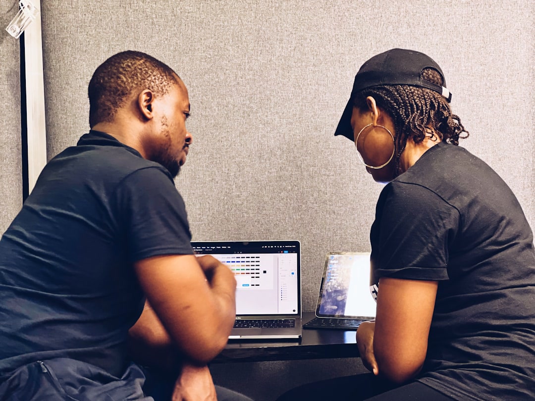 Contax360 BPO Solutions team in Jamaica, Offshore CX Confidence Index 2025: Two people seen from behind working on a laptop at a desk in a gray-walled booth