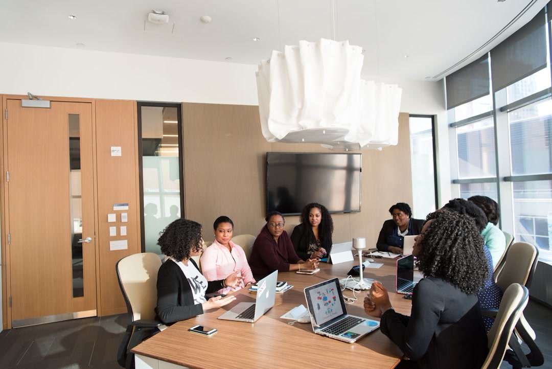 Contax360 BPO Solutions team in Jamaica, Offshore CX Confidence Index 2025: About seven women gathered around a wooden conference table with laptops, beside tall windows